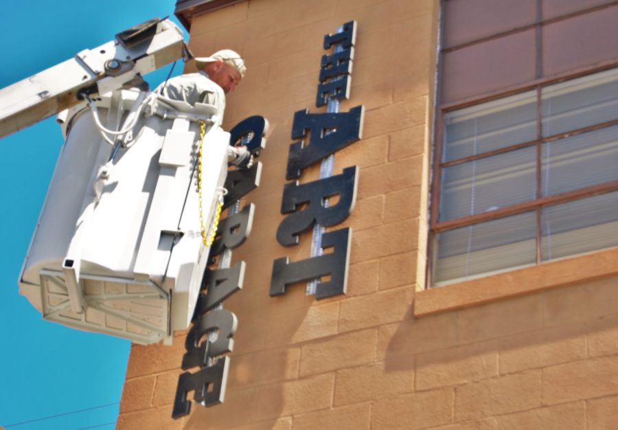 Workers put the finishing touches on the new sign at The Art Garage at Saint Francis